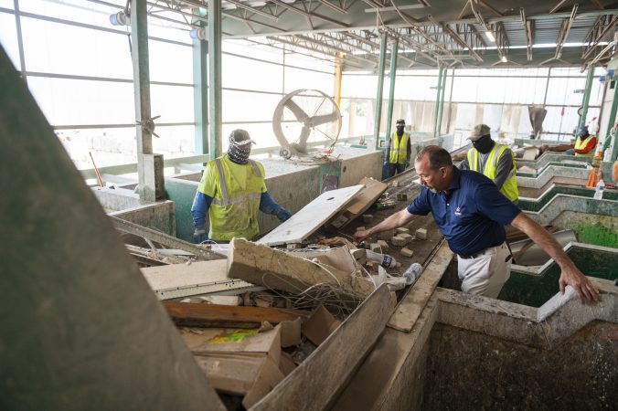 Allen T. Burns (right), owner of Burns Services, sorts through debris emptied from a TommyCart at the company's debris recycling plant in North Philadelphia.