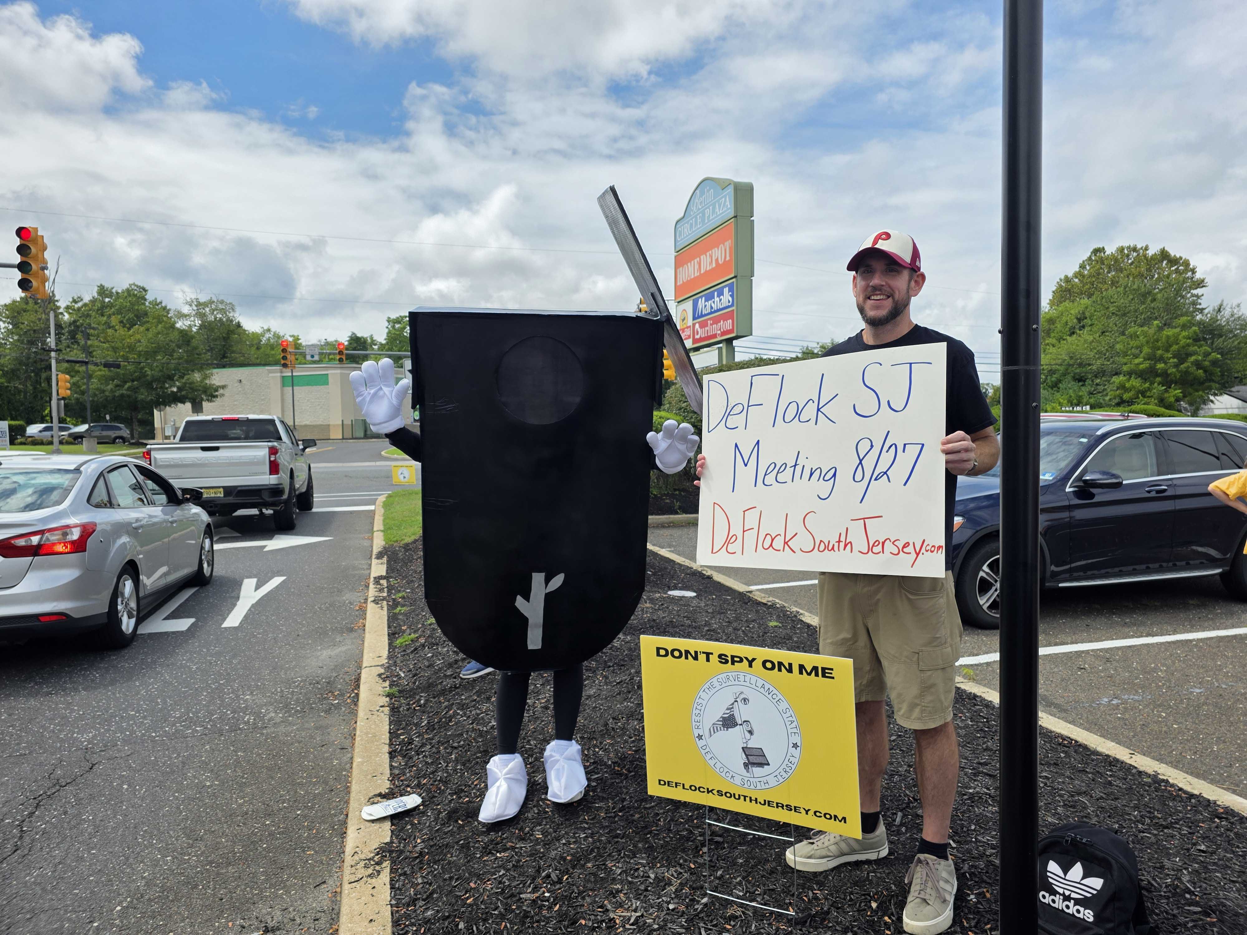 Adam Sheridan, an organizer with the new DeFlock South Jersey, alerts passing drivers to an organizing meeting in August where people hope to spread awareness regarding automated license plate readers. Flocky, a homemade mascot, acts as a visual boost.