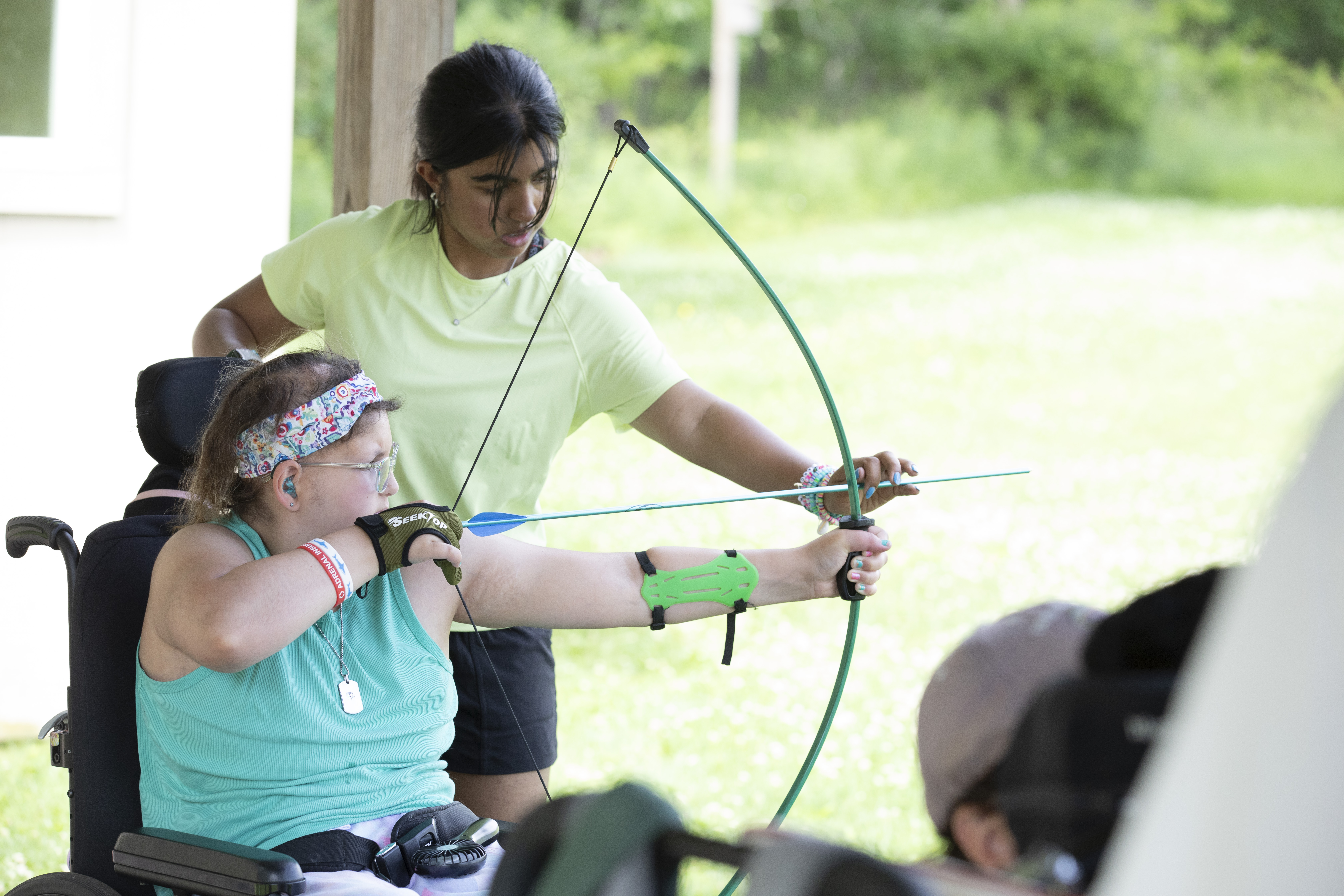 Camp Cranium counselor Anvitha Tharra (right) helps participant Angelica Zander learn to use a bow and arrow. The weeklong event in Pennsylvania’s Columbia County provides community, support, and fun for children with brain injuries. (Sarah Hofius Hall/WVIA News)