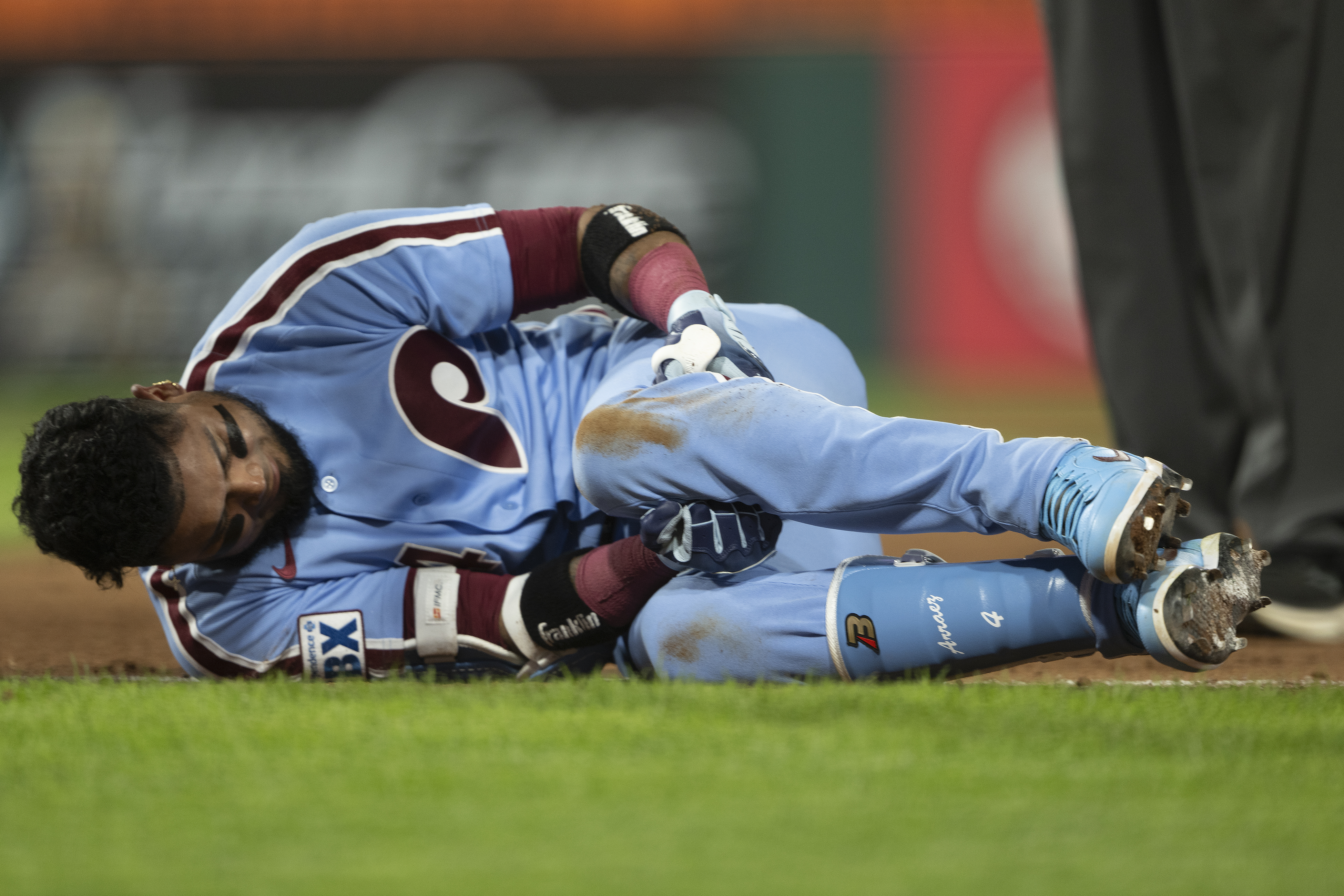 The Phillies’ Luis Arraez grabs his leg after falling to the ground while attempting to beat the throw to first base during the sixth inning.