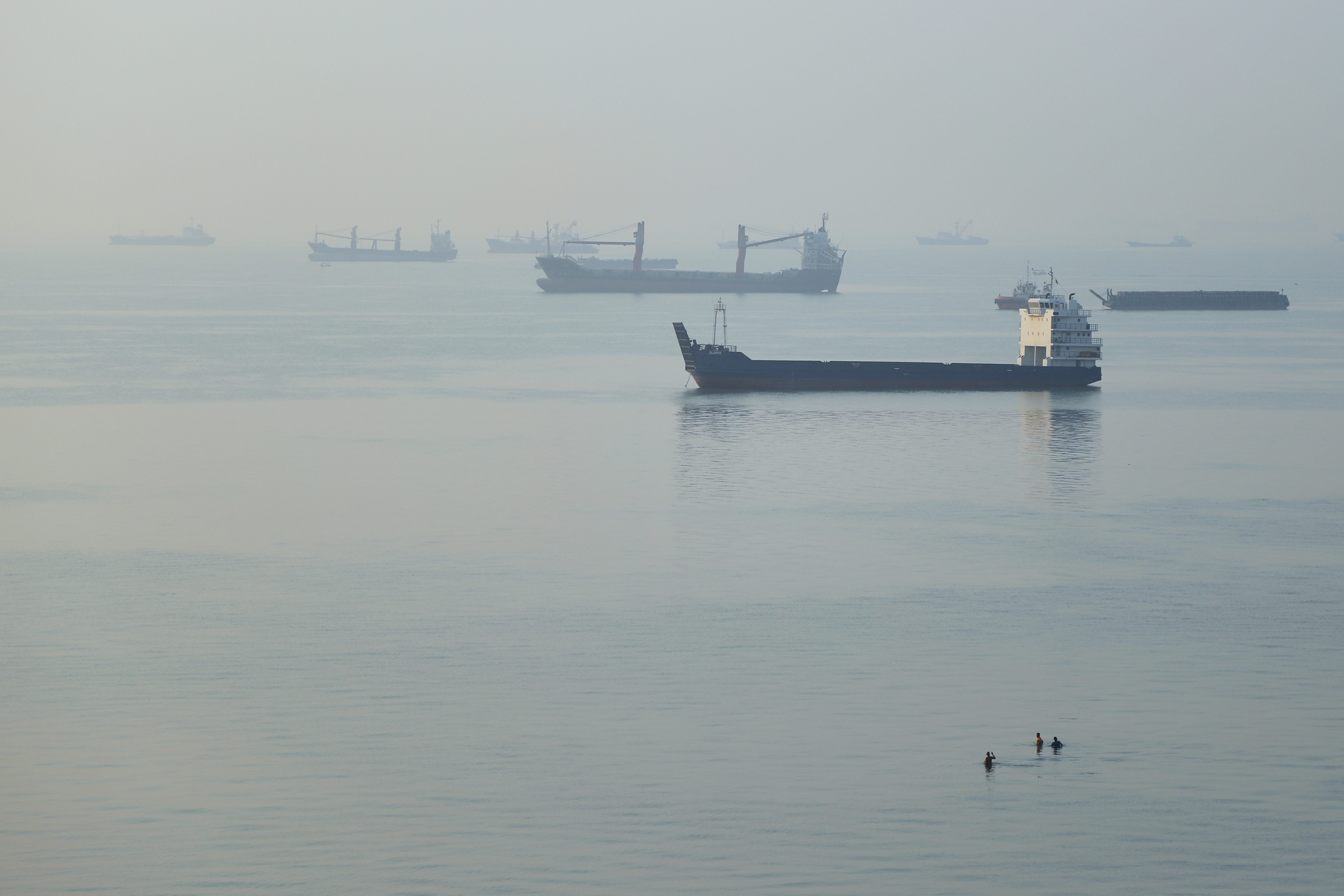 People wade in the water as cargo ships are anchored in the Strait of Hormuz off Bandar Abbas, Iran, early Monday, Sept. 28, 2026.