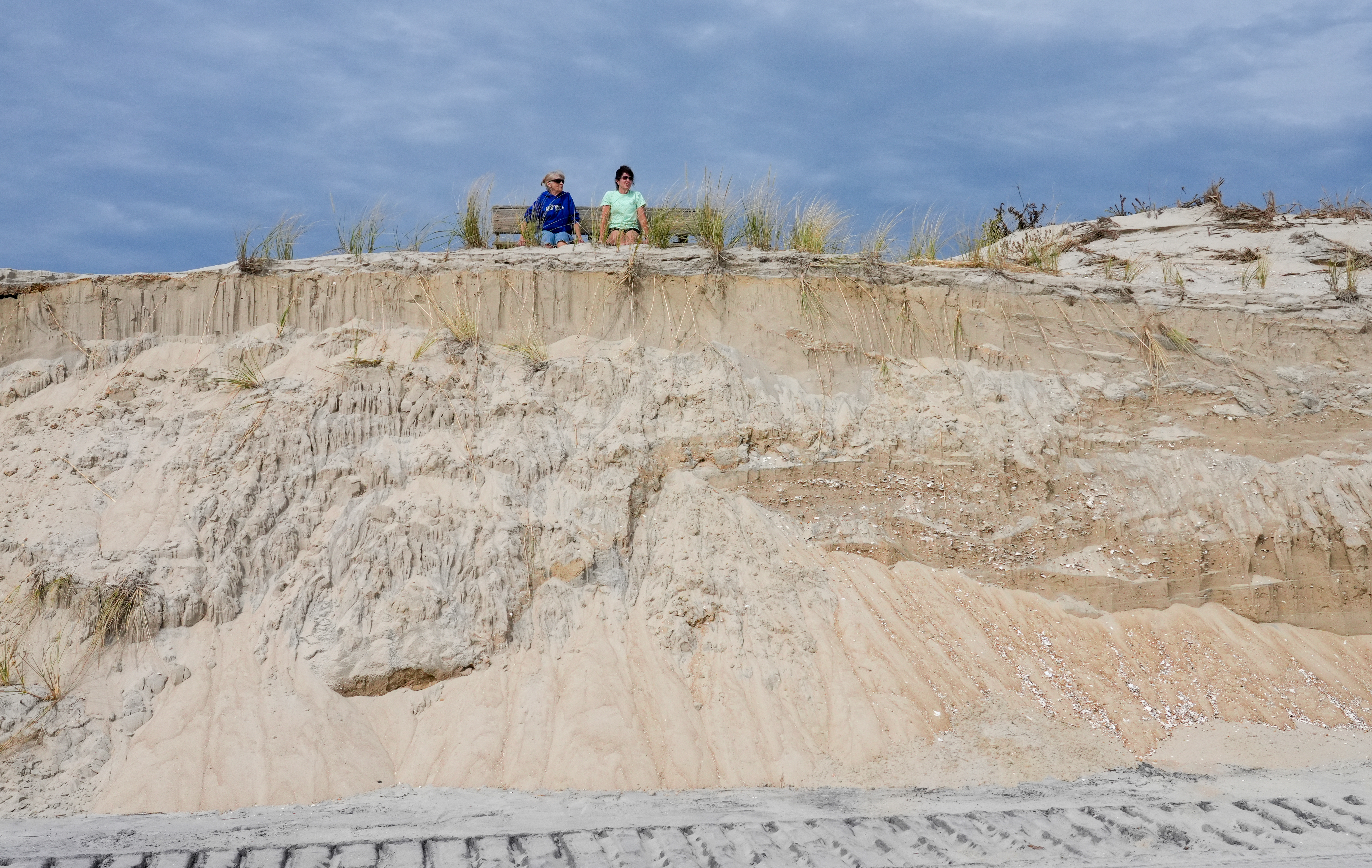 Gwen Moyer (left), of Hobbie, Pa., and her daughter Kim Crawford, of Bloomsburg, Pa., look out at the ocean as they sit above beach erosion in Holgate on Thursday.
